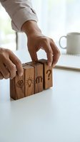Businessman hands arranging wooden blocks with brain, lightbulb, people and question mark symbols representing problem solving and strategic thinking process.