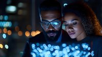 Young African American couple looking at glowing digital screen in dark with blue bokeh lights, creating modern tech atmosphere and intimate moment.