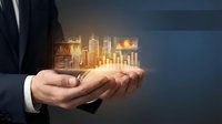 Businessman in dark suit holding glowing holographic cityscape with financial charts and upward trending graph, representing growth, investment, and digital economy.
