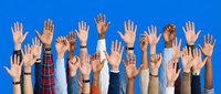 Diverse group of people raising hands against blue background showing unity, participation and volunteering spirit in community engagement.