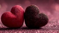 Two sparkling glittery hearts in red and burgundy colors on shimmering surface for romantic Valentine's Day celebration and love themed designs.