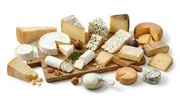 Assorted gourmet cheese selection with crackers nuts and herbs on wooden board for culinary presentations and food photography projects.