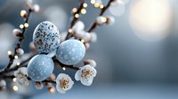 Delicate painted Easter eggs in soft blue with floral patterns nestled among blooming cherry branches and glowing bokeh lights create spring holiday atmosphere.