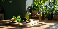 Freshil leaves on wooden board, olive oil bottles in sunlit kitchen setting with green plants and dramatic shadows.