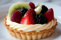 Fresh fruit tart with strawberries, kiwi, raspberries and blackberries on creamy custard filling in golden pastry shell for bakery menu dessert photography.