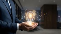 Businessman in blue suit holding glowing light bulb with sparkling particles, representing innovation, creativity, and business ideas in corporate environment.