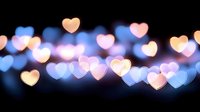Glowing heart shaped bokeh lights in pink and blue colors against dark background create romantic atmosphere for Valentine's day designs and love themes.