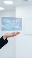 Businessperson holding holographic tablet displaying transportation vehicles including car, airplane, helicopter and ship with glowing wireframe designs in modern office environment.