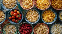 Fresh strawberries, raspberries and various types of dry pasta in decorative ceramic bowls arranged in rows on dark background, top view food composition.