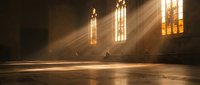 Sunbeams streaming through gothic church windows illuminating empty wooden pews in atmospheric golden light creating peaceful spiritual sanctuary interior.