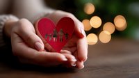 Female hands holding red paper heart with silhouette of family cutout against blurred bokeh lights background. Concept of family love, care and protection.