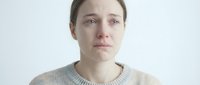 Young Caucasian woman with natural makeup and brown hair in casual beige sweater looking directly at camera against clean white background for portrait photography.