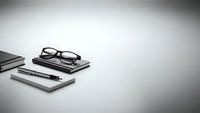 Minimalist black and white workspace with eyeglasses, notebook, and pen on clean desk surface for professional business and office concepts.