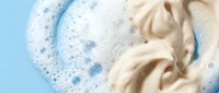 Creamy beige fabric softener with soap bubbles on blue background for laundry care and textile cleaning products advertising.