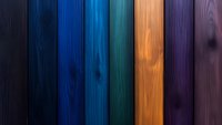 Colorful wooden planks in vertical arrangement featuring dark to bright tones of black, blue, turquoise, orange and purple. Natural wood grain texture creates depth.