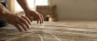 Professional carpenter hands measuring and marking wooden planks with precision tools for custom furniture construction project.