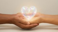 Two hands gently cupping a glowing translucent heart with rainbow light effects, symbolizing love, care, protection and emotional connection.