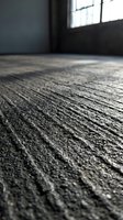 Rough textured concrete floor surface with natural sunlight streaming through industrial window creating dramatic shadows and depth in empty interior space.