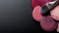 Makeup brush with pink and burgundy eyeshadow and blush palette on black leather background, perfect for beauty product photography.