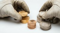 Hands in protective gloves stacking gold and silver coins on white background, numismatic collection and precious metal investment concept for finance and wealth management.