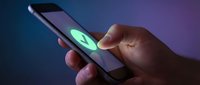 Hands holding smartphone with glowing green checkmark symbol on screen against blue and purple gradient background for approval, verification, success, and digital technology concepts.