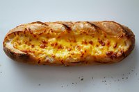 Twice baked potato loaded with melted cheddar cheese, sour cream and chives on white background, comfort food dish perfect for restaurant menus.