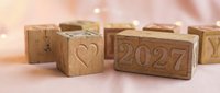Wooden blocks with heart symbol and 2027 number on pink background, representing love and new year planning.