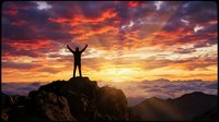 Silhouette of person with raised arms celebrating success on mountain peak at dramatic sunrise with vibrant orange and purple clouds over landscape.