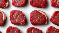 Fresh raw beef tenderloin steaks arranged in rows on white background, showing marbling texture and deep red color. Premium cut meat isolated for food photography.