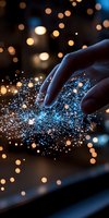 Magical glowing blue particles scatter from gentle finger touch against dark background with golden bokeh lights, creating ethereal digital interaction effect.