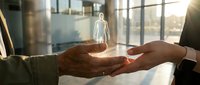 Business mentorship concept with glowing human figure hologram floating above cupped hands in modern office environment during golden hour.