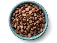 Chocolate cereal puffs in turquoise ceramic bowl on white background, overhead view. Crispy breakfast food isolated, ready for commercial and packaging design use.