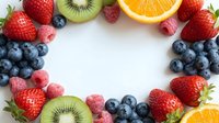 Fresh mixed berries and fruits arranged in circular frame on white background creating colorful border for healthy eating and nutrition concepts.
