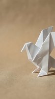 White origami bird folded from paper standing on a beige craft surface, showcasing Japanese paper art and minimalist handmade creativity.