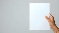 Female hand with manicured nails pointing at blank white paper against neutral background, suitable for presentations, advertising, and marketing materials.
