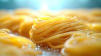 Fresh homemade pasta noodles in close-up with soft focus background, showcasing golden yellow color and delicate texture for culinary and food photography.