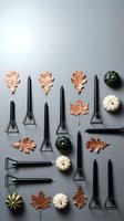 Autumn flat lay with black candles, copper leaves and mini pumpkins arranged on gray background for seasonal home decor and crafting projects.