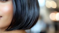 Close up portrait of young Asian woman with black bob haircut and natural makeup against blurred bokeh background, focus on hair texture and style.