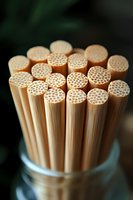 Macro view of natural bamboo drinking straws showing honeycomb structure ends arranged in glass jar, eco-friendly alternative to plastic, sustainable lifestyle.