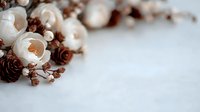Autumn floral arrangement with white roses, pine cones and dried branches on light wooden background. Natural seasonal decor for wedding invitations.