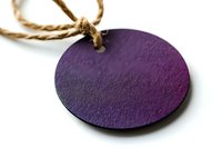 Round purple wooden pendant with natural twine cord on white background, isolated craft jewelry piece for design projects and creative use.