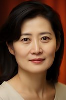 Professional headshot portrait of young Asian woman with natural makeup and gentle smile against warm red background, wearing neutral top.