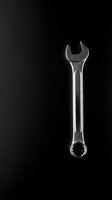 Chrome wrench tool isolated on black background with dramatic lighting for automotive repair and maintenance projects.