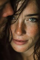 Close-up portrait of young Caucasian woman with freckles and green eyes in natural lighting with tousled brown hair for beauty and skincare concepts.