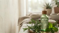 Essential oil bottle with fresh herbs on wooden tray in bright living room. Natural aromatherapy and wellness concept for spa treatments and relaxation.