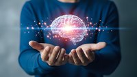 Person in blue shirt holding glowing brain with digital connections representing artificial intelligence, machine learning and neuroscience innovation.