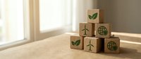 Wooden blocks with green eco symbols including leaves, wind turbines and globe icons arranged on natural surface representing sustainable business concepts.