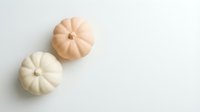 Two small decorative pumpkins in cream and peach colors on white background, autumn seasonal decor for fall harvest celebration and thanksgiving design.