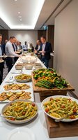 Corporate catering buffet with fresh salads, pasta dishes and grilled vegetables served at business meeting in modern conference room for professional events.