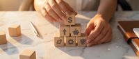 Business professional arranging wooden blocks with financial icons including dollar sign and gears on desk for strategic planning and growth concepts.